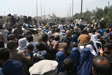Afghans gather on a roadside near the military part of the airport in Kabul on August 20, 2021, hoping to flee from the country after the Taliban's military takeover of Afghanistan. (AFP)