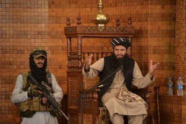 An Imam speaks next to an armed Taliban fighter during Friday prayers at the Abdul Rahman Mosque in Kabul on August 20, 2021. (AFP)