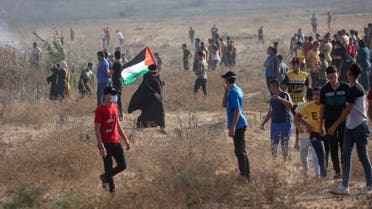 A Palestinian protester lifts a national flag as she takes part in a demonstration by the border fence with Israel, east of Gaza City on August 21, 2021. (Said Khatib/AFP)