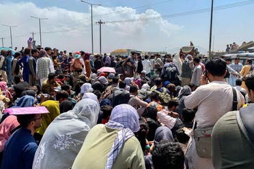 Afghan people gather along a road as they wait to board a US military aircraft to leave the country, at a military airport in Kabul on August 20, 2021 days after Taliban’s military takeover of Afghanistan. (AFP)