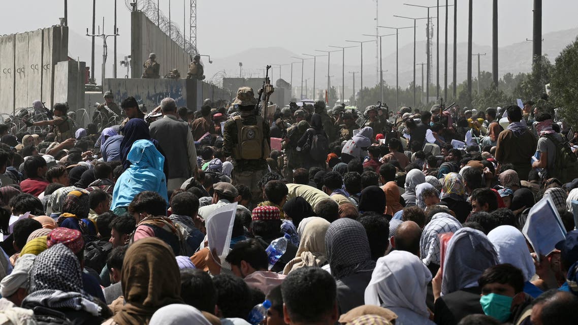 Afghans gather on a roadside near the military part of the airport in Kabul on August 20, 2021, hoping to flee from the country after the Taliban's military takeover of Afghanistan. (AFP)