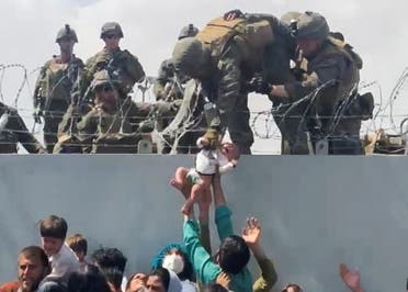 A baby is handed over to the American army over the perimeter wall of the airport for it to be evacuated, in Kabul, Afghanistan, August 19, 2021. (Reuters)