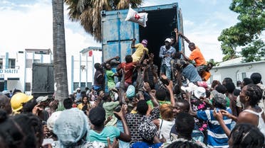 A man throws a bag of rice into a crowd of earthquake victims gathered for the distribution of food and water at the “4 Chemins” crossroads in Les Cayes, Haiti on August 20, 2021. (Reginald Louissaint JR/AFP)