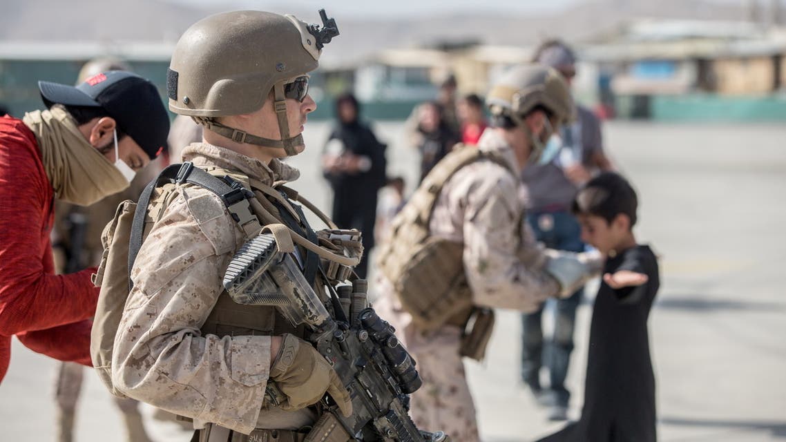 A US Marine provides assistance during an evacuation at Hamid Karzai International Airport, Kabul, Afghanistan, August 21, 2021. (Reuters)