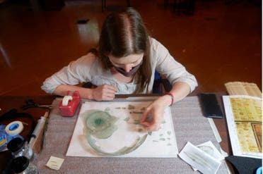 Claire Cuyaubère a specialist conservator sent by the French National Institute of Cultural Heritage to analyze the shattered glass artifacts engages in the process of puzzle work. (Supplied)