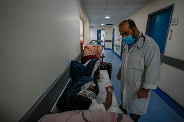 Doctor Jihad Bikai checks on a patient who is lies in a bed at crowded government-run Rafik Hariri University Hospital corridor in Beirut, Lebanon, Wednesday, Aug. 11, 2021. (AP/Hassan Ammar)