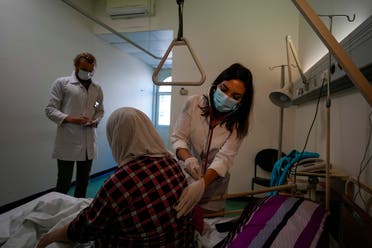 Ghaidaa al-Saddik, internal medicine resident doctor checks on a patient at government-run Rafik Hariri University Hospital in Beirut, Lebanon, Wednesday, Aug. 11, 2021. (AP/Hassan Ammar)