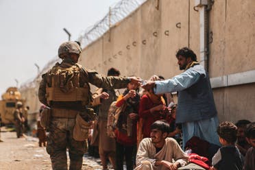 A US Marine passes out water to evacuees during an evacuation at Hamid Karzai International Airport, Kabul, Afghanistan, August 22, 2021. (Reuters)