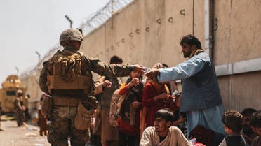A U.S. Marine passes out water to evacuees during an evacuation at Hamid Karzai International Airport, Kabul, Afghanistan, August 22, 2021. (Reuters)