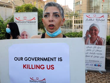 A cancer patient holds a sign, during a sit-in demonstration as shortages of cancer medications spread, in front of the UN headquarters in Beirut, Lebanon August 26, 2021. (Reuters)