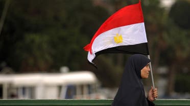 An Egyptian woman walks with her national flag on Qasr el-Nil bridge leading to Cairo's Tahrir Square. (File photo: AFP)