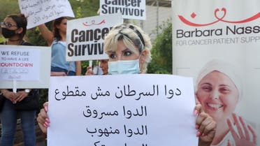 Christine Tohme, a cancer patient, holds a sign during a sit-in demonstration as shortages of cancer medications spread, in front of the UN headquarters in Beirut, Lebanon August 26, 2021. (Reuters)