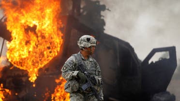 Captain Melvin Cabebe with the US Army's 1-320 Field Artillery Regiment, 101st Airborne Division stands near a burning M-ATV armored vehicle after it struck an improvised explosive device (IED) near Combat Outpost Nolen in the Arghandab Valley north of Kandahar, Afghanistan. (File photo: Reuters)