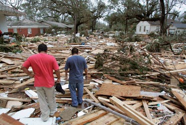People walk amidst the remains of the St Charles Condominiums and Sadler Apartments in Biloxi, Mississippi, August 29, 2005, which were pushed up between the private homes on St Charles Street by the storm surge from Hurricane Katrina. (Reuters)