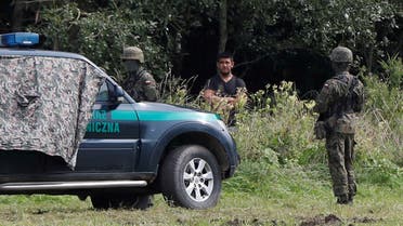 Polish border patrol officers are pictured next to a migrant stranded on the border between Belarus and Poland near the village of Usnarz Gorny, Poland, on August 23, 2021. (Reuters)