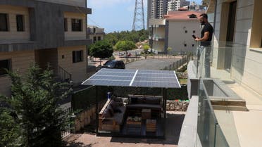 Mohammad Chehab stands on a balcony as he looks at a solar panel he installed at his home in Khaldeh, Lebanon August 25, 2021. (Reuters)