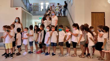 An Israeli teacher welcomes pupils wearing protective face masks upon their return to the new school year amid a surge of COVID-19 cases in Israel, at Beit Hakerem Israeli elementary school in Jerusalem, on September 1, 2021. (Menahem Kahana/AFP)