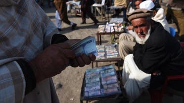 In this photograph taken on December 29, 2014, an Afghan customer (L) counts his Afghani currency notes at a currency exchange market along the roadside in Kabul. (File photo: AFP)