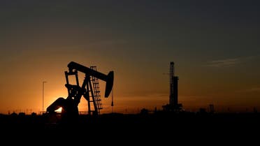 A pump jack operates in front of a drilling rig at sunset in an oil field in Midland, Texas, US. (Reuters)