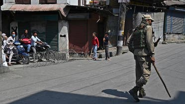 A paramilitary trooper patrols a street as commuters watch in the downtown area of Srinagar on September 3, 2021, as thousands of Indian security forces maintained a lockdown across Kashmir after the death of a separatist political leader sparked clashes with protesters. (AFP)