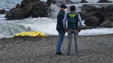 A file photo shows Spanish Guardia Civil members stand next to the body of a migrant at the beach of the Spanish enclave of Ceuta on May 20, 2021. (Antonio Sempere/AFP)