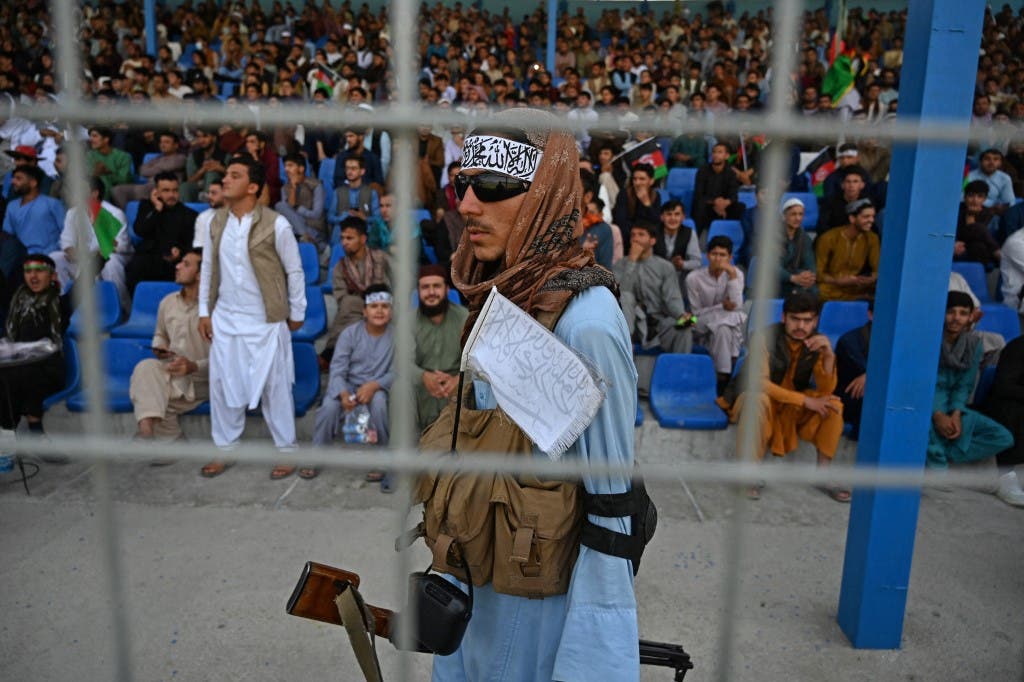 A Taliban fighter (C) keeps vigil as spectators watch the Twenty20 cricket trial match being played between two Afghan teams at the Kabul International Cricket Stadium in Kabul on September 3, 2021. (AFP)