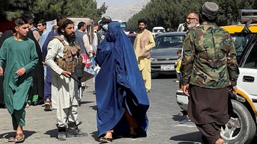Taliban forces block the roads around the airport, while a woman with Burqa walks passes by, in Kabul, Afghanistan. August 27, 2021. (Reuters)