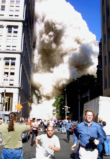 This 11 September 2001 file photo shows pedestrians running from the scene as one of the World Trade Center towers collapses in New York City following a terrorist plane crash on the twin towers. (AFP)