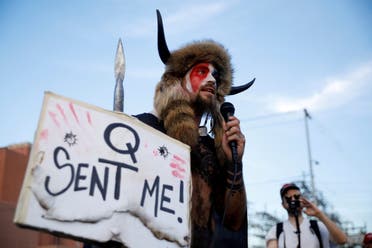 Jacob Chansley, holding a sign referencing QAnon, speaks as supporters of U.S. President Donald Trump gather to protest about the early results of the 2020 presidential election, in front of the Maricopa County Tabulation and Election Center (MCTEC), in Phoenix, Arizona November 5, 2020. (File Photo: Reuters)
