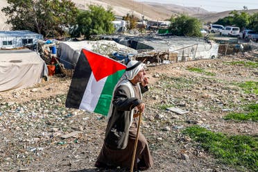 A Bedouin man walks with a Palestinian flag in the village of Khan al-Ahmar in the Israeli-occupied West Bank on November 29, 2020. (AFP)
