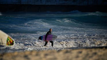 A surfer walks at Bondi Beach in Sydney on August 18, 2021. (AFP)