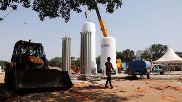 A man walks in front of newly installed oxygen tanks at the construction site of a temporary coronavirus care facility, at Ramlila Ground, in New Delhi, India, May 12, 2021. (Reuters)