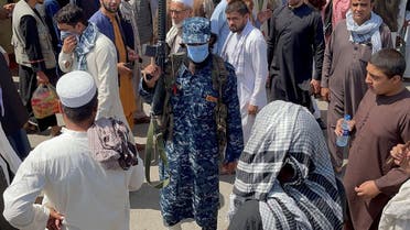 A member of Taliban security forces stands guard among crowds of people walking past in a street in Kabul, Afghanistan. (Reuters)