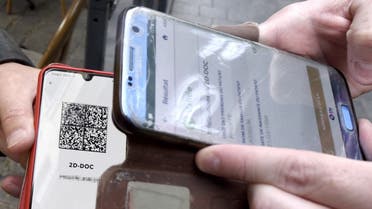 A waiter checks a customer's Covid-19 health pass on a mobile phone at the entrance of his cafe in Valenciennes, northern France, on August 9, 2021. (AFP)