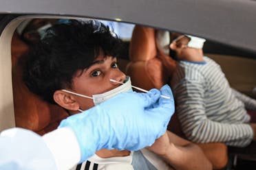 A medical staffer obtains a swab sample from a child inside a vehicle at a drive-through COVID-19 coronavirus testing centre in al-Khawaneej district of the gulf emirate of Dubai on April 9, 2020. (File photo: AFP)