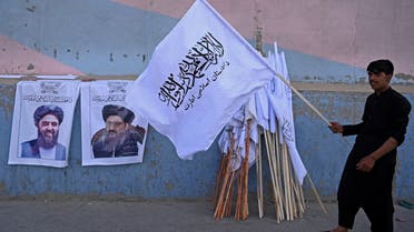A vendor holds a Taliban flag next to the posters of Taliban leaders Mullah Abdul Ghani Baradar and Amir Khan Muttaqi (L) as he waits for customers along a street in Kabul on August 27, 2021. (AFP)