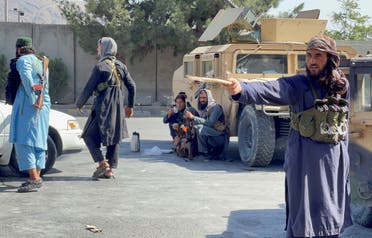 عنصر من طالبان يوجه عصاه نحو محتجين(رويترز)