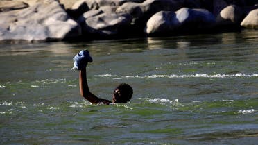 An Ethiopian fleeing fighting in Tigray region lifts his clothes as he crosses the Setit river on the Sudan-Ethiopia border in Hamdayet village in eastern Kassala state, Sudan. (File photo: Reuters)