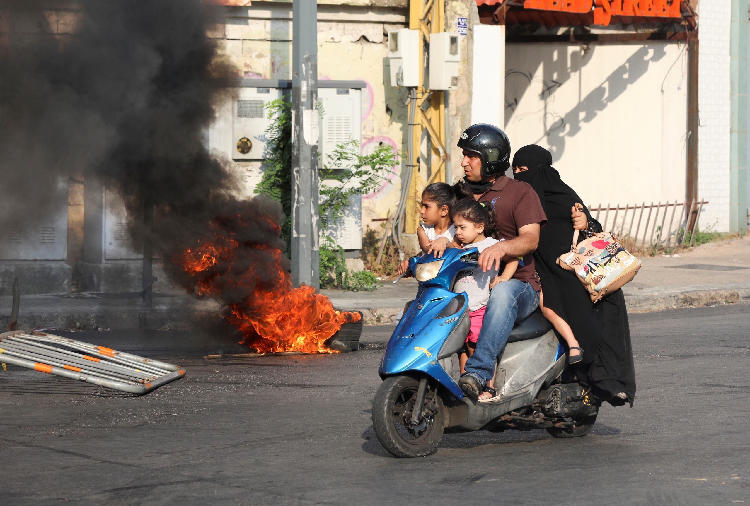 A man rides on a motorbike past a burning tyre, during a demonstration by relatives of some of the victims of last year's Beirut port blast, near the Justice Palace in Beirut, Lebanon July 14, 2021. (File photo: Reuters)