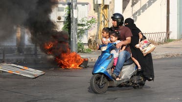 A man rides on a motorbike past a burning tyre, during a demonstration by relatives of some of the victims of last year's Beirut port blast, near the Justice Palace in Beirut, Lebanon July 14, 2021. (File photo: Reuters)