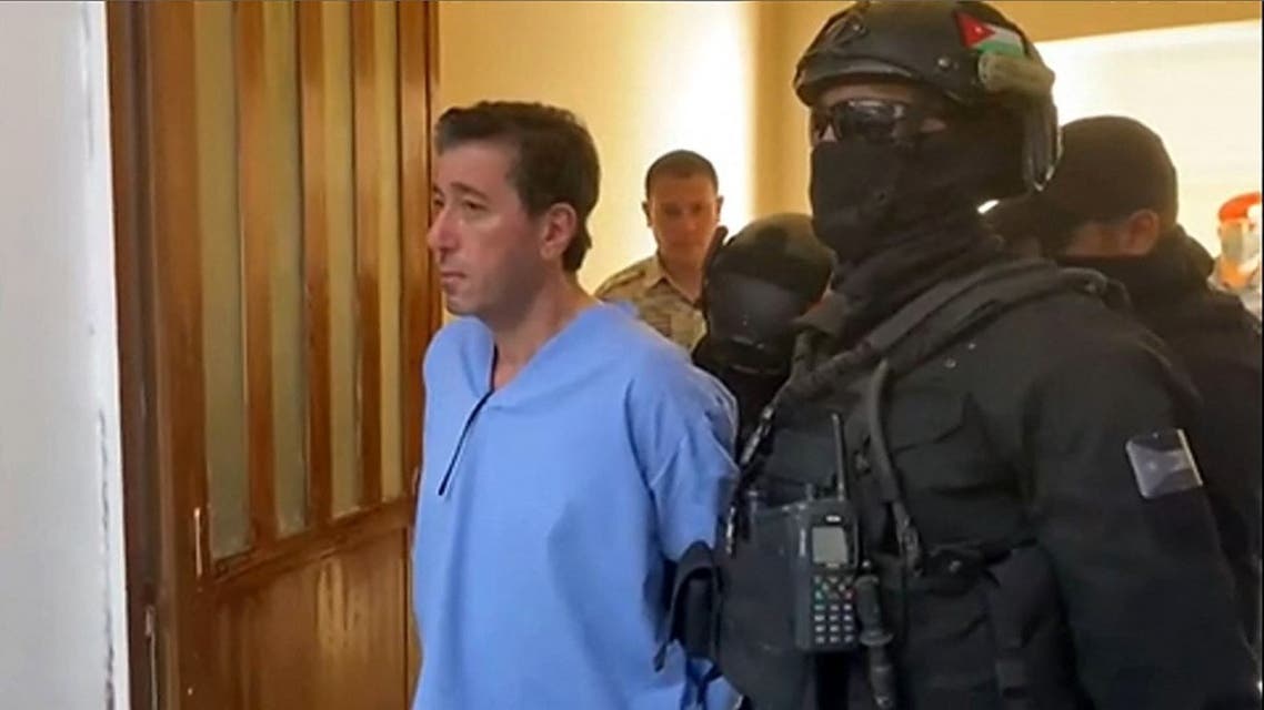This video grab obtained from a footage released by Jordan Television on June 12, 2021 shows Bassem Awadallah, one of two former officials convicted of conspiring to topple King Abdullah II in favour of his half-brother Prince Hamzah, being escorted by security personnel into the State Security Court in the Jordanian capital Amman. (AFP)