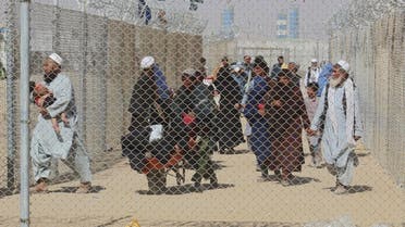 Afghan people walk inside a fenced corridor as they enter Pakistan at the Pakistan-Afghanistan border crossing point in Chaman on August 25, 2021 following the Taliban's stunning military takeover of Afghanistan. (AFP)