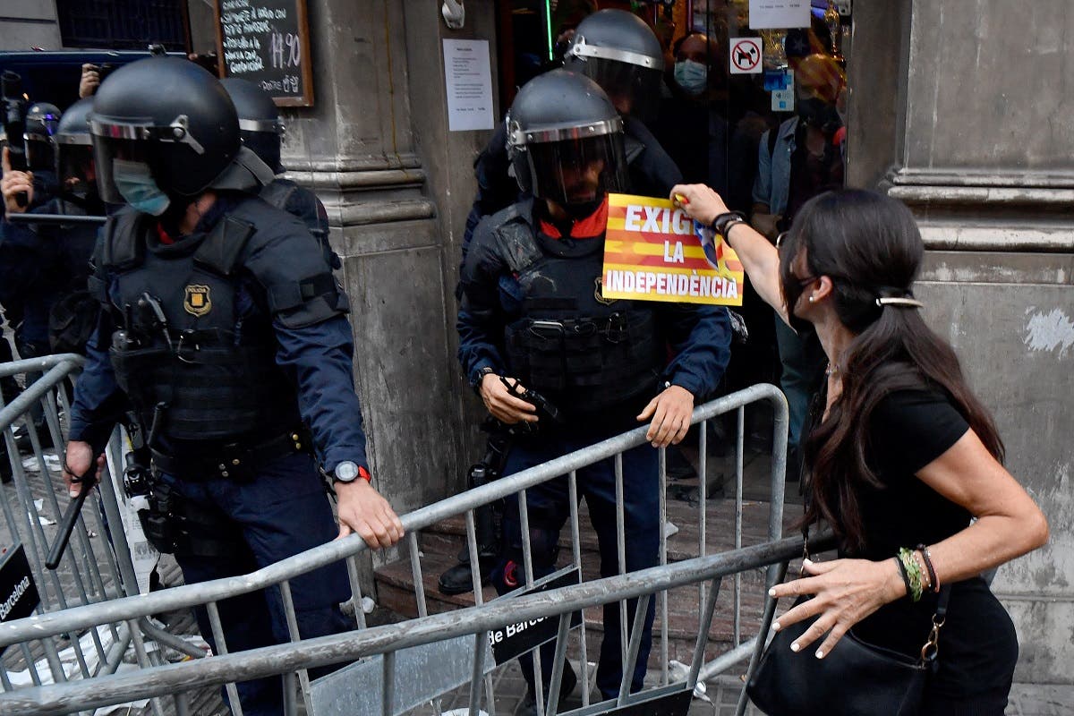 A demonstrator shows a pamphlet fo a member of the Catalan regional police forces following a demonstration marking the Diada, national day of Catalonia, in Barcelona on September 11, 2021. (AFP)