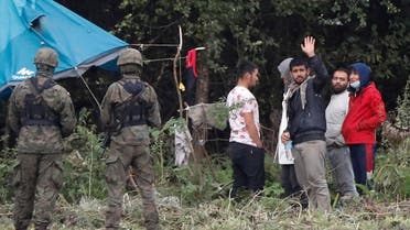Polish border guard officers stand guard next to a group of migrants stranded on the border between Belarus and Poland near the village of Usnarz Gorny. (Reuters)