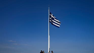 Tourists stand under a Greek flag on the Acropolis hill in Athens on June 8, 2021. (AFP)