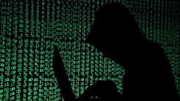 A hooded man holds a laptop computer as cyber code is projected on him in this illustration picture taken on May 13, 2017. (Reuters)