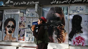 A Taliban fighter walks past a beauty salon with images of women defaced using spray paint in Shar-e-Naw in Kabul on August 18, 2021. (AFP)