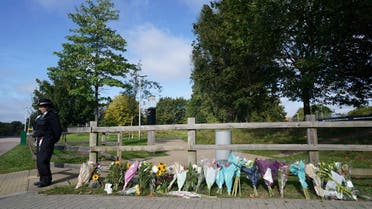 A police officer stands by floral tributes at Cator Park in Kidbrooke, near to the area where the body of Sabina Nessa was found, in London, on Sept. 23, 2021.  (AP)