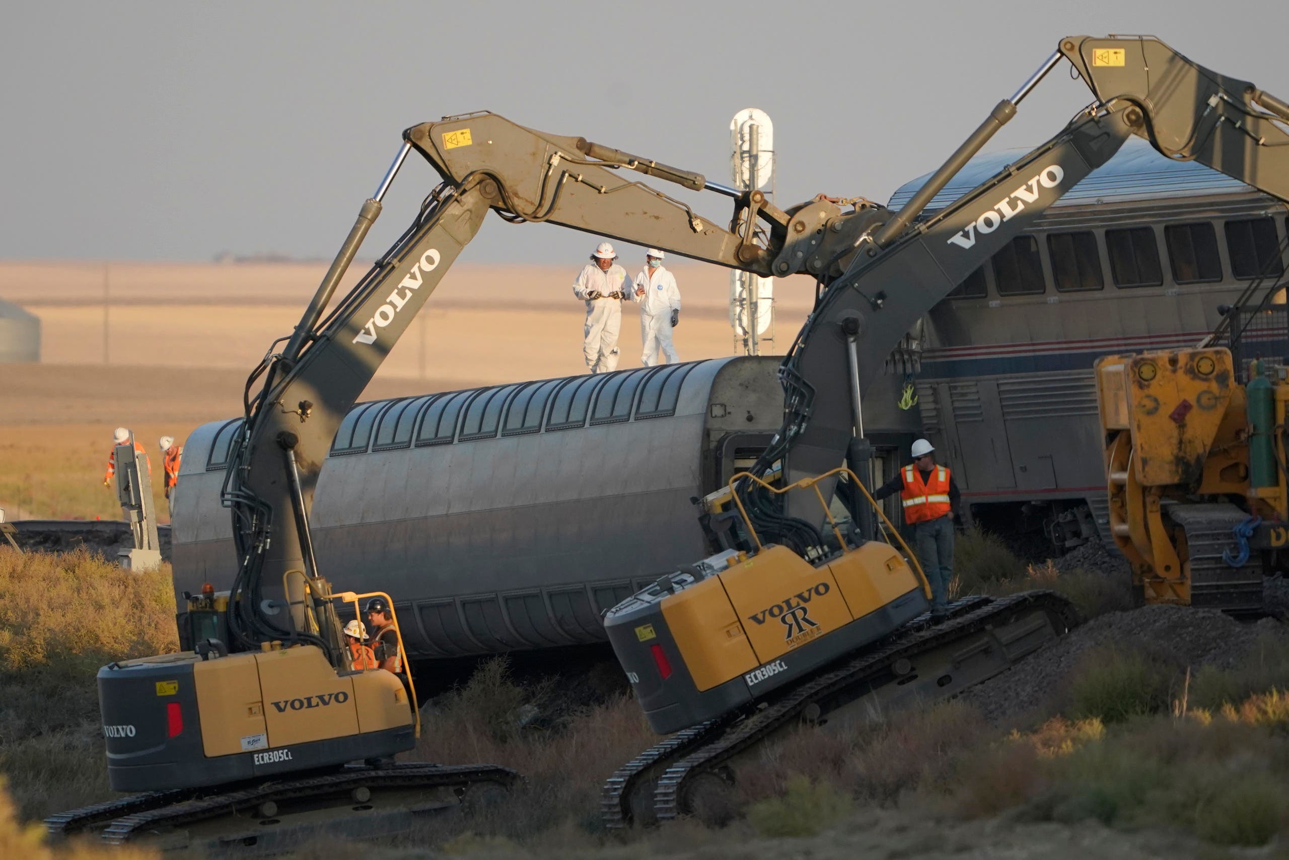 Workers stand on a train car on its side as front-loaders prop up another train car, Sunday, Sept. 26, 2021, from an Amtrak train that derailed Saturday, just west of Joplin, Mont. The westbound Empire Builder was en route to Seattle from Chicago with two locomotives and 10 cars. (AP)