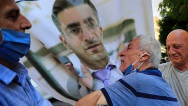The father of Ibrahim Harb, 35, center, a Lebanese man who was critically injured in the massive explosion at Beirut's port last year and who died on Monday nearly 14 months after the blast, mourns on his son's portrait during his funeral procession, in Beirut, Lebanon, Tuesday, Sept. 28, 2021. (AP)